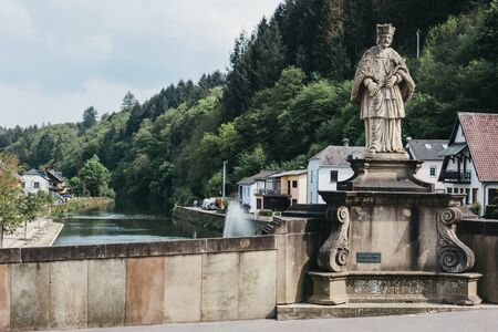 Vianden, Luxembourg - May 18, 2019: Statue of Saint John of Nepomuk on a bridge over the river Our in Vianden, a town in Luxembourgs Ardennes region known for the centuries-old hilltop Vianden Castle.のeditorial素材