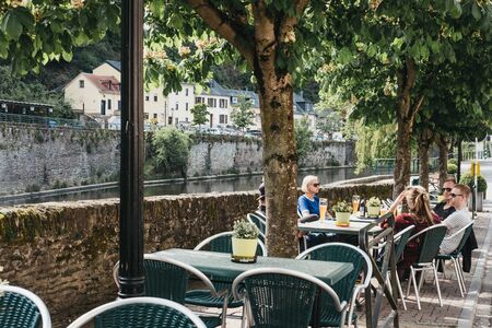 Vianden, Luxembourg - May 18, 2019: People sitting at cafe tables by the river Our in Vianden, a town in Luxembourgs Ardennes region known for the centuries-old hilltop Vianden Castle.のeditorial素材