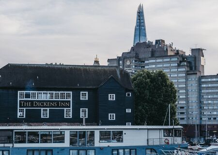 London, UK - June 22, 2019: The Dickens Inn pub in St. Katharine Docks, a former dock converted into marina and commercial and residential district in Central London, Shard on the background.のeditorial素材