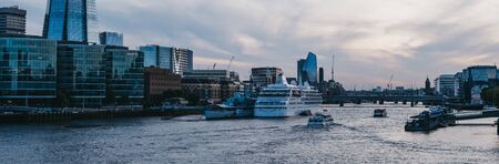 London, UK - June 22, 2019: Panoramic view of large holiday cruise ship moored on River Thames by HM Belfast during blue hour. London is one of the most visited cities in the world.のeditorial素材