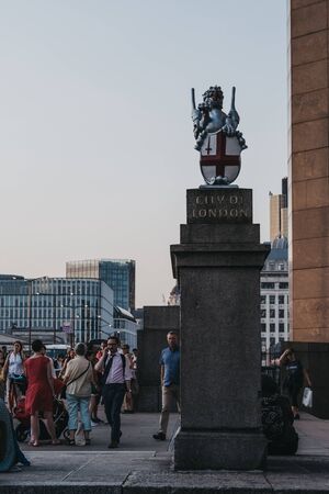 London, UK - July 23, 2019: People walk past Dragon statue by the City of London boundary in London Bridge, at dusk, selective focus. The City of London is a historic financial district.のeditorial素材