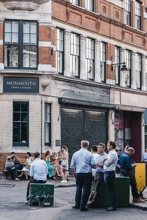 London, UK - July 23, 2019: People standing and drinking on a street outside cafes and pubs in...