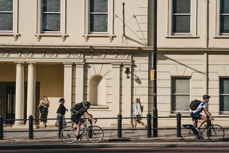 London, UK - July 16, 2019: People cycling on a street in Pimlico, London, during golden hour, selective focus. Cycling is a popular way of getting around the city.のeditorial素材