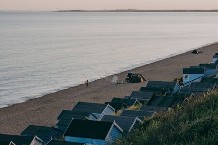 Milford on Sea, UK - July 13, 2019: People camping and fishing on a beach by the huts in Milford on Sea, a traditional English village famous for breathtaking cliff top walks and great pebble beachesのeditorial素材