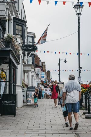 Lymington, UK - July 14, 2019: People walking under the colourful bunting on a street in Lymington, New Forest, a historic coastal town with an ancient seaport and a rich maritime history.のeditorial素材