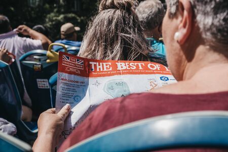 London, UK - July 29, 2019: Woman looking at route map on top deck of tour bus in London on a bright summer day. Open top bus tours are amongst the most popular tourist activities in London.のeditorial素材