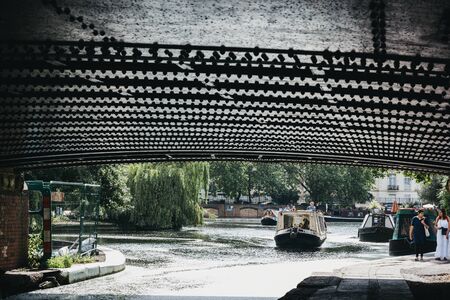 London, UK - July 18, 2019: View from under the bridge of boats on a sunny day on Regents Canal in Little Venice, London, a tranquil area of the city where the Grand Union and Regentâs canals meet.のeditorial素材