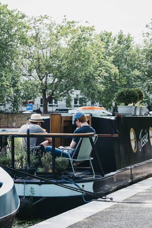 London, UK - July 18, 2019: View of people relaxing and reading on a boat on Regents Canal in Little Venice, London, a tranquil area of the city where the Grand Union and Regentâs canals meet.のeditorial素材