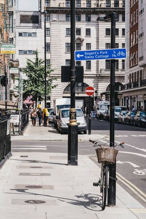 London, UK - July 18, 2019: Bicycle by a lamppost and people walking in distance on a street in Marylebone, a chic residential area of London famous for Baker Street and Madame Tussauds waxwork museumのeditorial素材