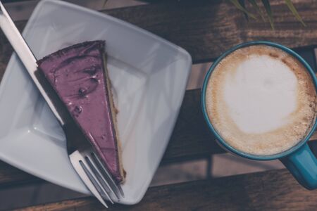 View from above of a fresh cup of coffee and a slice of berry cake on a wooden table, selective focus.の写真素材