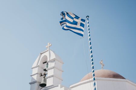 Greek flag waving in the wind against blur sky, over the orthodox chapel. Motion blur.の写真素材