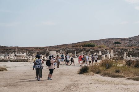 Delos, Greece - September 20, 2019: People walking amongst the ruins on island of Delos, an archaeological site in Greece near Mykonos in the Aegean Sea Cyclades archipelago.のeditorial素材