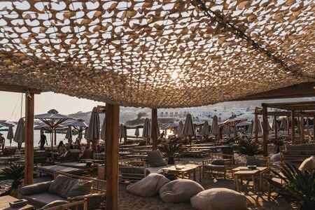 Mykonos, Greece - September 19, 2019: Tables and rows of sun beds and parasols on Platis Gialos, a popular beach on the south coast of Mykonos. Selective focus.のeditorial素材
