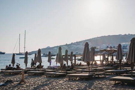 Mykonos, Greece - September 19, 2019: Rows of sun beds and parasols on Platis Gialos, a popular beach on the south coast of Mykonos. Selective focus.のeditorial素材