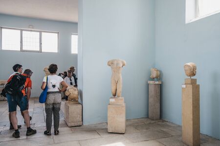 Delos, Greece - September 20, 2019: Statues inside the Archaeological Museum of Delos, a museum on the historic island of Delos in the South Aegean, Greece, people walking by, selective focus.のeditorial素材