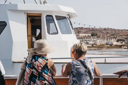 Mykonos Town, Greece - September 20, 2019: Women talking on a deck of a tour boat to Delos from Hora (Mykonos Town), capital of the island and one of the best examples of Cycladic architecture.のeditorial素材
