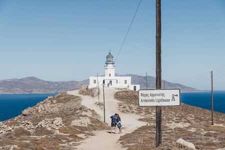 Mykonos, Greece - September 23, 2019: Sign on the approach to Armenistis Lighthouse in Mykonos, Greece, people walking on background. Lighthouse was built in 1891 and is an iconic sight of Mykonos.のeditorial素材