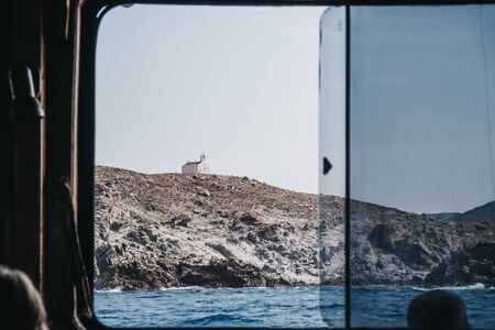 View of the typical Mykonian church on a hill from the window of a boat, Mykonos, Greece.の写真素材