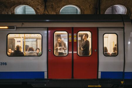 London, UK - November 26, 2019: London Underground train on a station platform, people seen though the window. London Underground is the oldest underground railway in the world. Selective focus.のeditorial素材