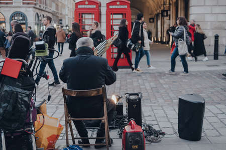 London, UK - March 06, 2020: Rear view of a street musician in Covent Garden, London, a famous tourist area in London with lots of shops and restaurants. Selective focus.のeditorial素材