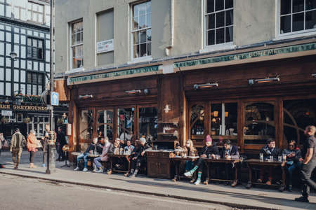 London, UK - March 06, 2020: People sitting at the outdoor tables of Cafe Boheme in Soho, an area of London famous for LGBTQ+ bars, on a sunny spring day.のeditorial素材