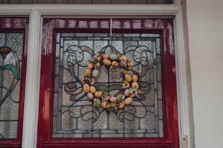 Close up of an Easter egg wreath on a stained glass door of an Edwardian house in London, UK.の写真素材