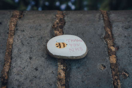 London, UK - April 12, 2020: Pebble painted with thank you NHS message left on the street as people...