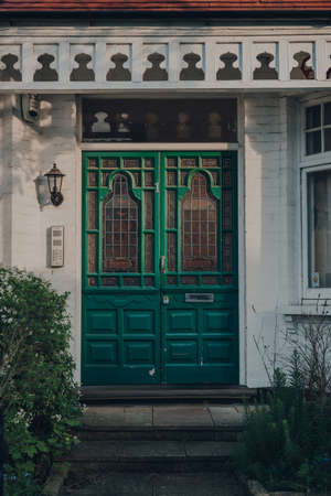 London, UK - April 12, 2020: Stained glass bright green wooden door of a traditional Edwardian house in London, UK. Edwardian houses promote simple design and an appreciation for the handmade.のeditorial素材