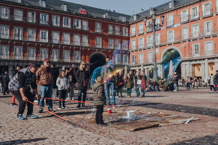 Madrid, Spain - January 26, 2020: Street performer creates a soap bubble around a boy in Plaza Mayor, a major public space in the heart of Madrid, Spain.のeditorial素材