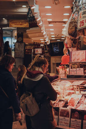 Madrid, Spain - January 26, 2020: Women looking at a variety of Jamon (Ham) on sale inside shop  in Madrid, capital of Spain renowned for its rich repositories of European art, selective focus.のeditorial素材