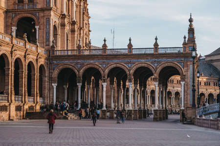 Seville, Spain - January 17, 2020: People amongst arches on Plaza de EspaÃ±a, a plaza in the Parque de MarÃ­a Luisa, in Seville, Spain, built in 1928 for the Ibero-American Exposition of 1929.のeditorial素材