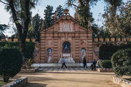 Seville, Spain - January 17, 2020: Monument to Catalina de Ribera in Jardines de Murillo, urban park in Seville with paved walkways, benches & shade trees, people walking past, motion blur.のeditorial素材