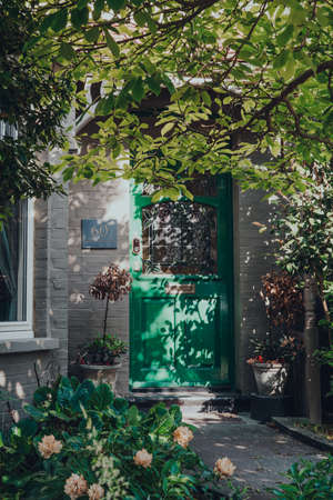 London, UK - May 30, 2020: Green stained glass front door of an Edwardian house in London, sun coming through the leaves. Edwardian houses promote simple design and an appreciation for the handmade.のeditorial素材