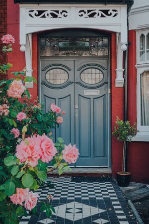 Grey front door of a traditional Edwardian house in London, UK, view over blossoming roses, selective focus.の写真素材