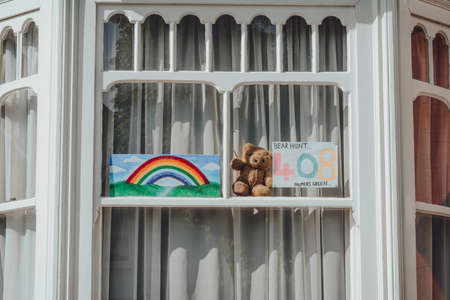 London, UK - June 06, 2020: Rainbow sign, teddy bear and a bear hunt number displayed in a window of a house in London as people entertain passing by kids during Coronavirus related restrictions.のeditorial素材