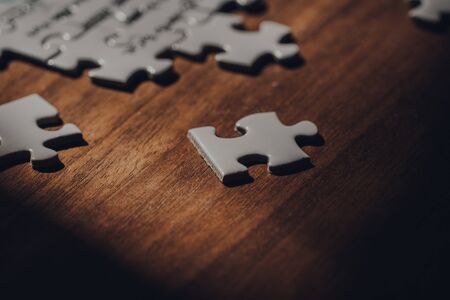 White puzzle piece on a walnut wooden table, selective focus.の写真素材