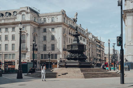 London, UK - June 13, 2020: Woman taking photo of Eros statue in empty Piccadilly Circus, one of the...