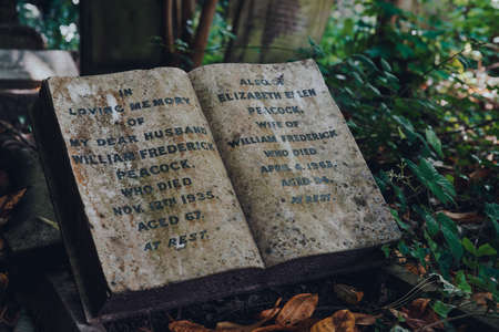London, UK - June 16, 2020: Book-shaped tombstone for wife and husband inside Hampstead Cemetery, a historic cemetery in West Hampstead, London, opened in November 1876. Selective focus.のeditorial素材