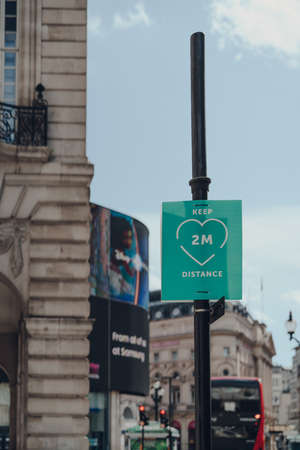 London, UK - June 13, 2020: Keep two metres distance green sign on a Regent Street, a major shopping street in London, Piccadilly Circus on the background, selective focus.のeditorial素材
