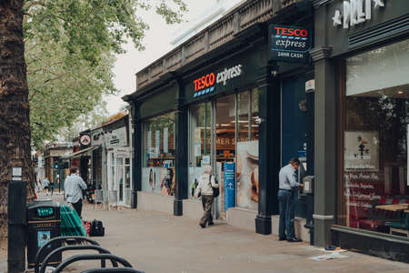 London, UK - June 20, 2020: People outside Tesco supermarket and cafes in Holland park, an affluent...