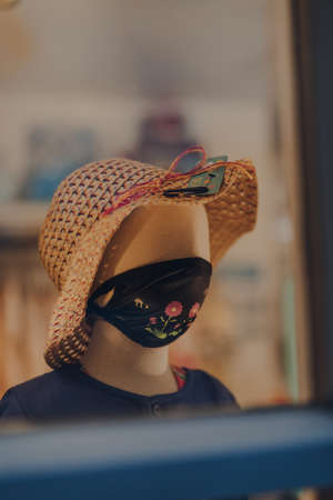 Stow-on-the-Wold, England - July 6, 2020: View through the window of mannequins on shop display wearing a face mask. Face masks will be compulsory in shops in England from 24th July. Selective focus.のeditorial素材