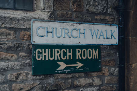Street name sign and a directional arrow to church room on a limestone building on Church Walk in Stow on the Wold, Cotswolds, UK, selective focus.の写真素材
