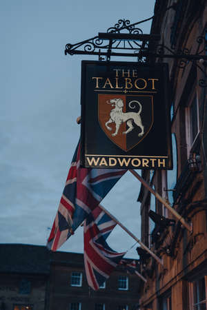 Stow-on-the-Wold, UK - July 6, 2020: Sign outside The Talbot pub in Stow-on-the-Wold, a market town in Cotswolds build on Roman Fosse Way, Union Jack flags on the background, in the evening.のeditorial素材