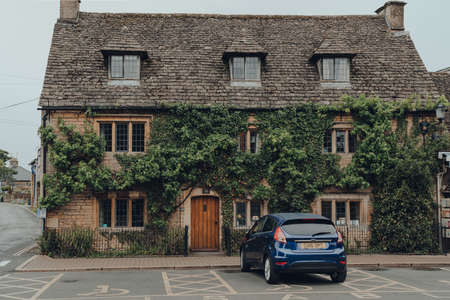Bourton-on-the-Water, UK - July 10, 2020: A typical Cotswolds cottage home in Bourton-on-the-Water, a famous village in rural Cotswolds area of England. Covered in ivy, car parked at the front.のeditorial素材