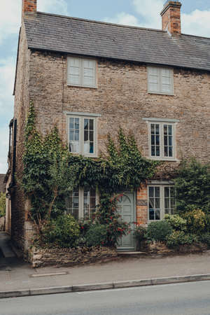 Stow-on-the-Wold, UK - July 10, 2020: Facade of a traditional stone house covered in climber plants...