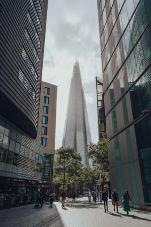 London, UK - August 25, 2020: View of The Shard between the buildings on More London, people walking in front. The Shard is are one of the most popular landmarks in London.のeditorial素材