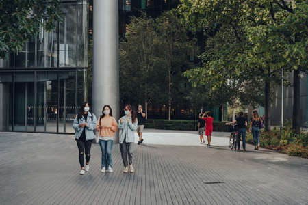 London, UK - August 25, 2020: Women in face masks walk on More London, a part of London Bridge City...