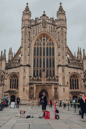 Bath, UK - October 04, 2020: Street performer playing violin in front of a cathedral in Bath, the largest city in the county of Somerset, England, known for and named after its Roman-built baths.のeditorial素材