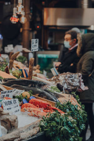 London, UK - November 19, 2020: Fresh fish on sale at a fishmonger stall in Borough Market, one of the largest and oldest food markets in London, customer on the background, selective focus.のeditorial素材