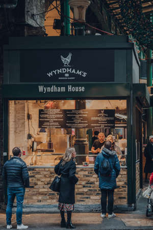London, UK - November 19, 2020: People socially distanced queuing at a Wyndham take away food stall in Borough Market, one of the largest and oldest food markets in London.のeditorial素材